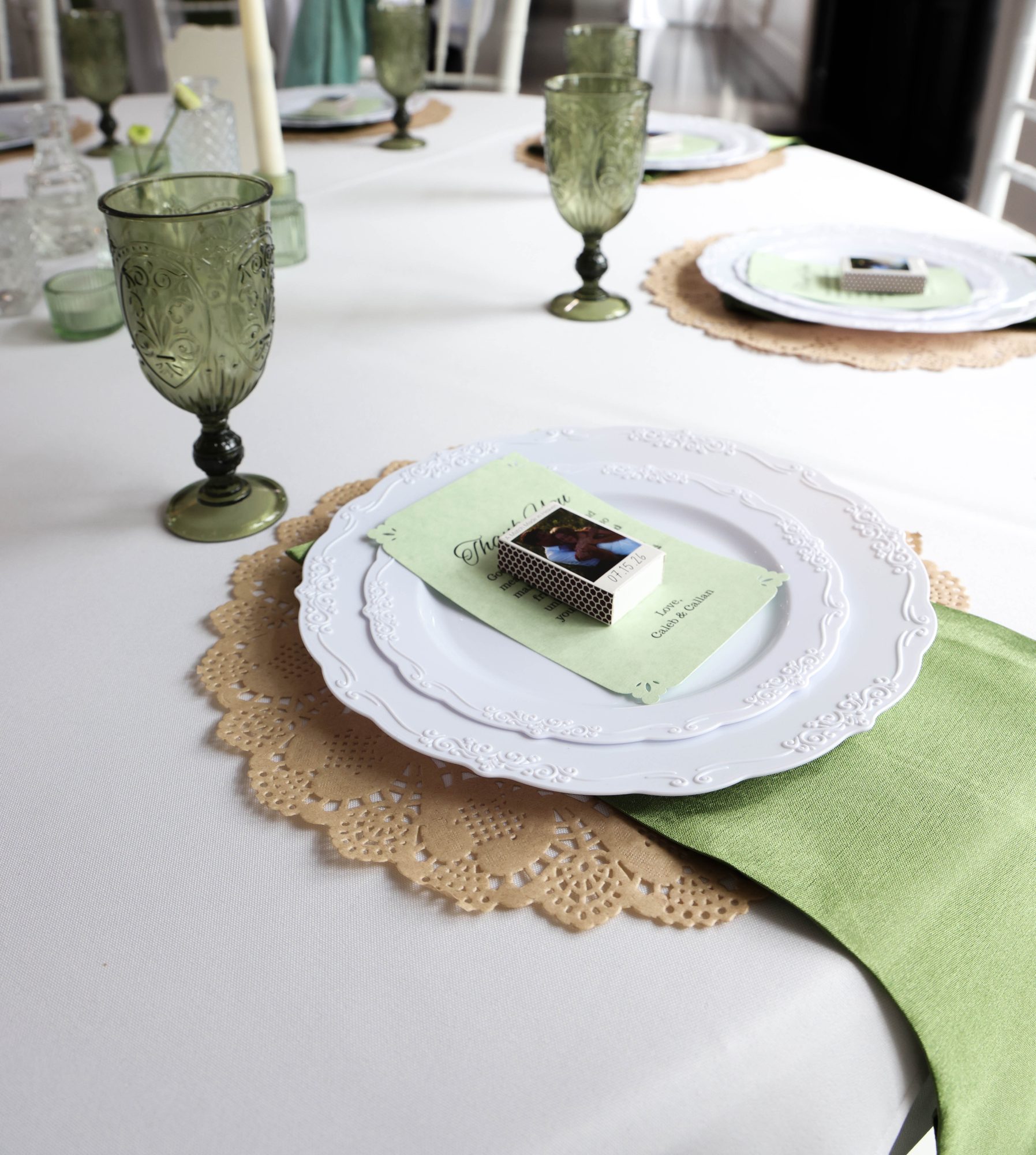 Reception place setting with green glassware and a sage napkin