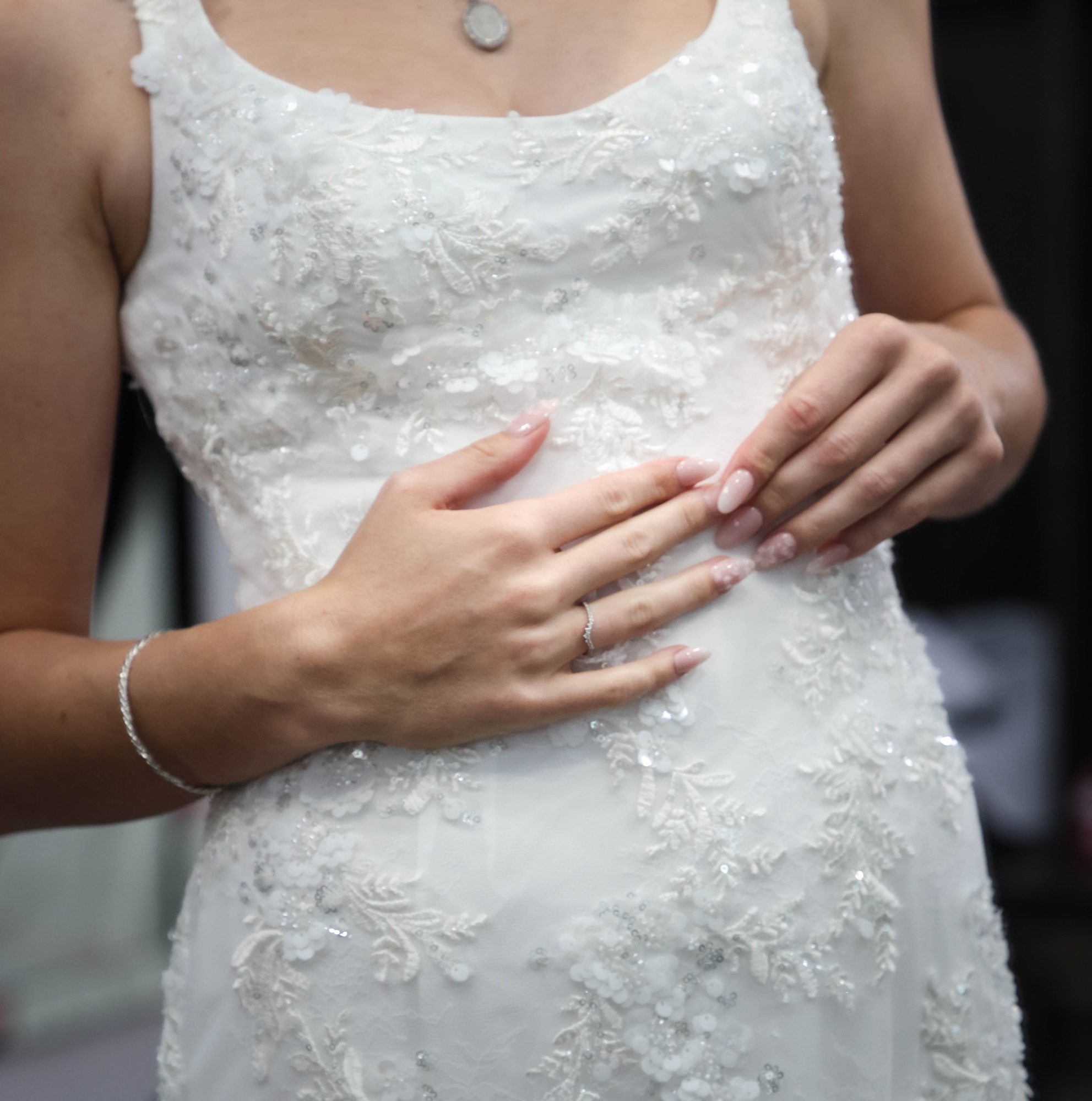 Close-up of the bride’s lace gown and wedding ring