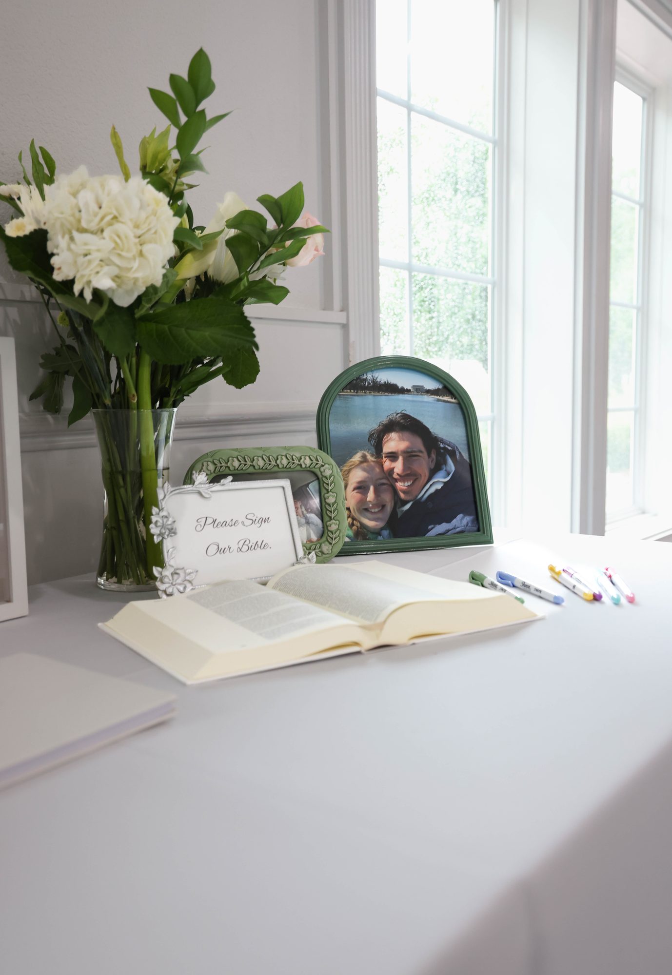 Guest book table with white flowers and a framed photo of the couple