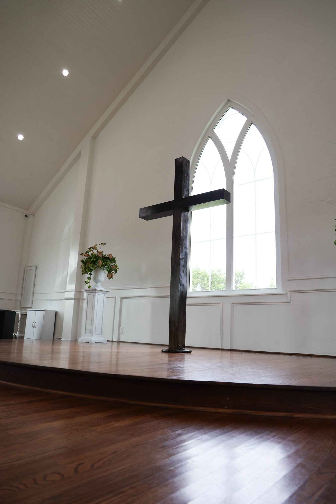 Chapel interior with a wooden cross beneath an arched window