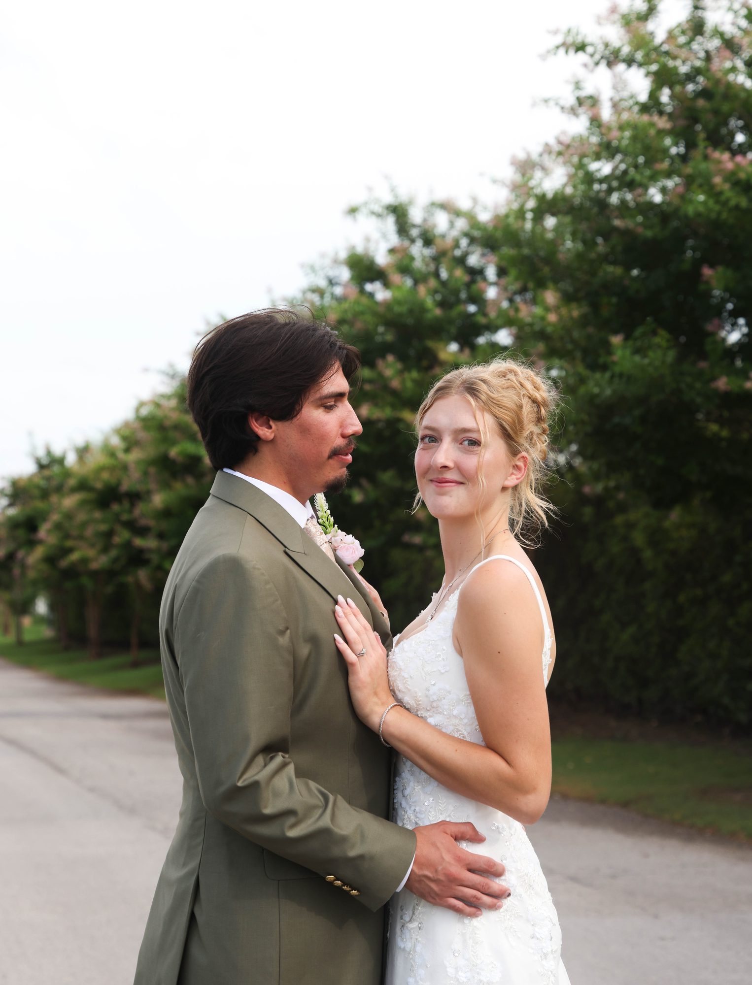 Bride and groom embracing on a tree-lined lane