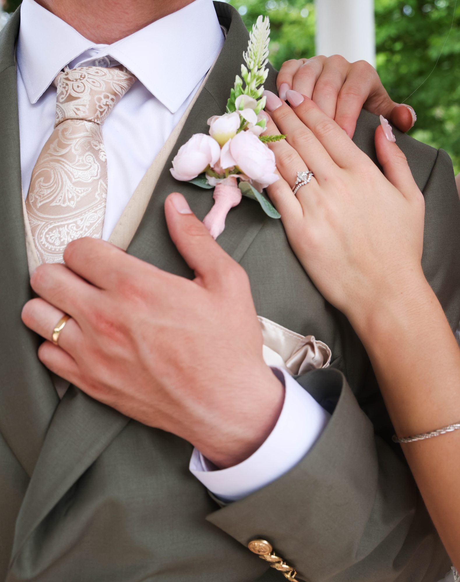 Close-up of the couple’s hands and rings on the groom’s lapel
